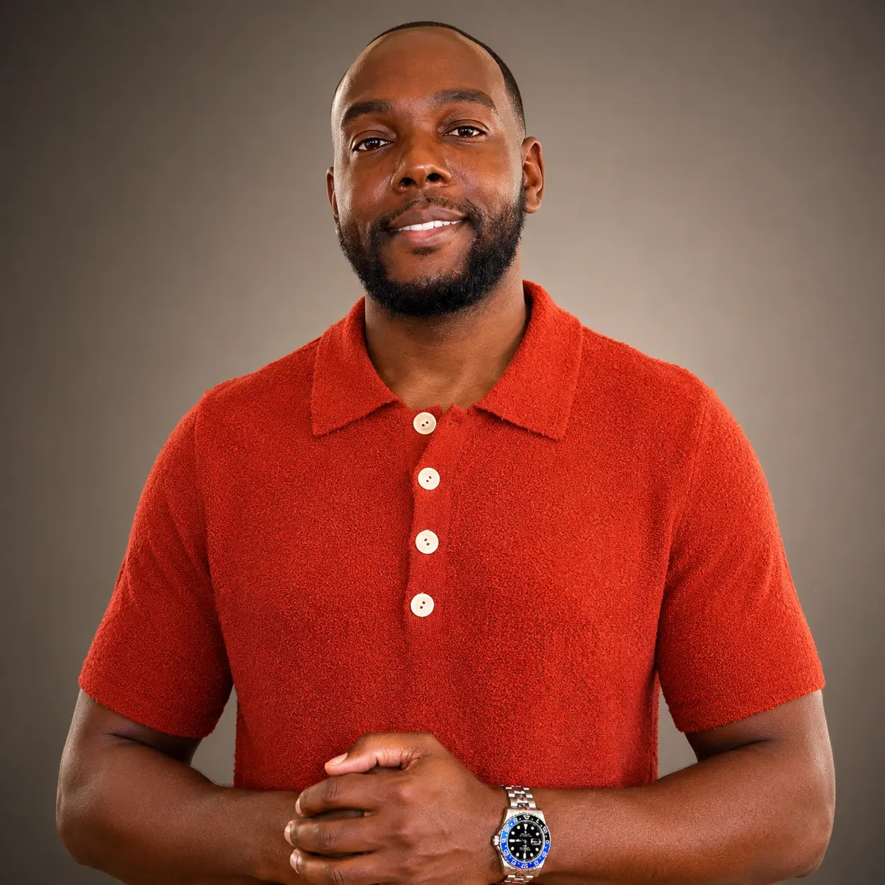 Estimé in an orange polo, smiling